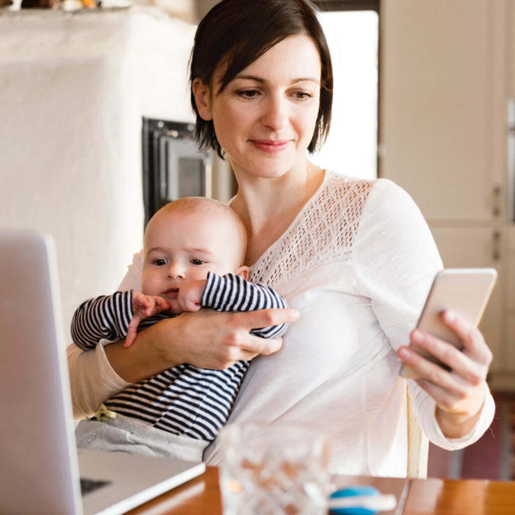 Woman holding baby and view app on phone